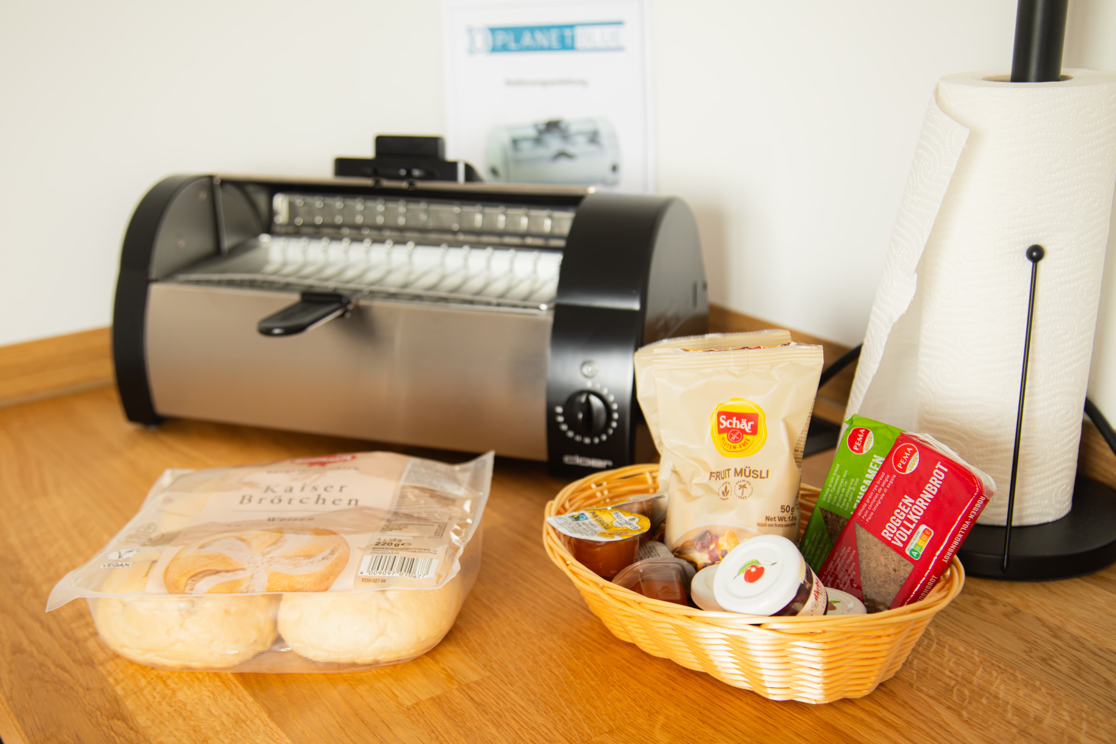 Brötchenofen mit Aufbackbrötchen, Korb mit Müsli, Aufstrichen und Aufschnitt