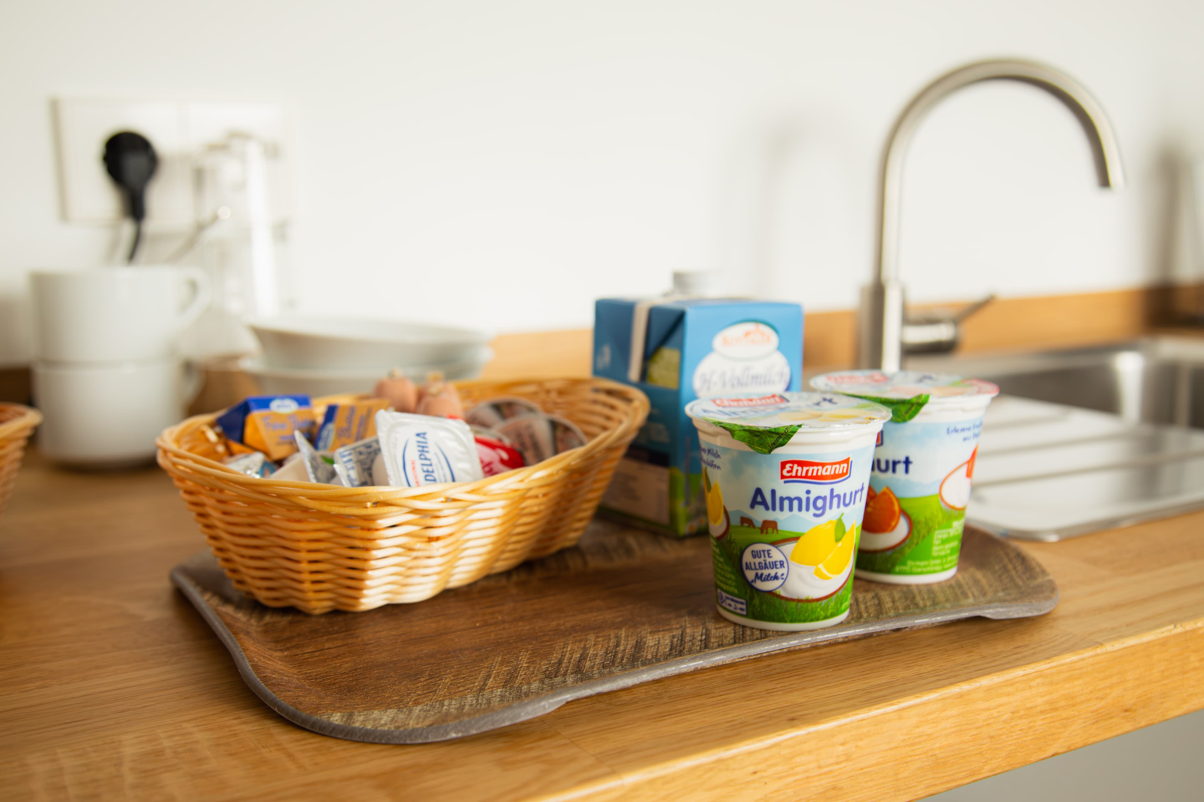 Servierbrett mit Aufschnitt-Korb, Almighurt und Vollmilch auf der Küchenzeile