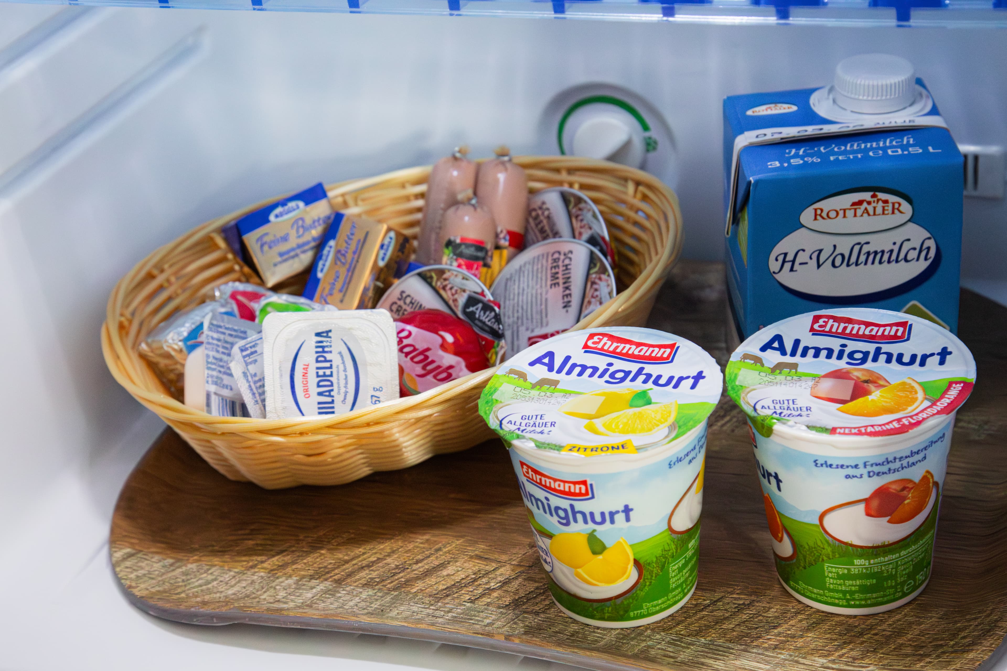 Aufschnitt-Korb, Wurst, Vollmilch und Almighurt im geöffneten Kühlschrank